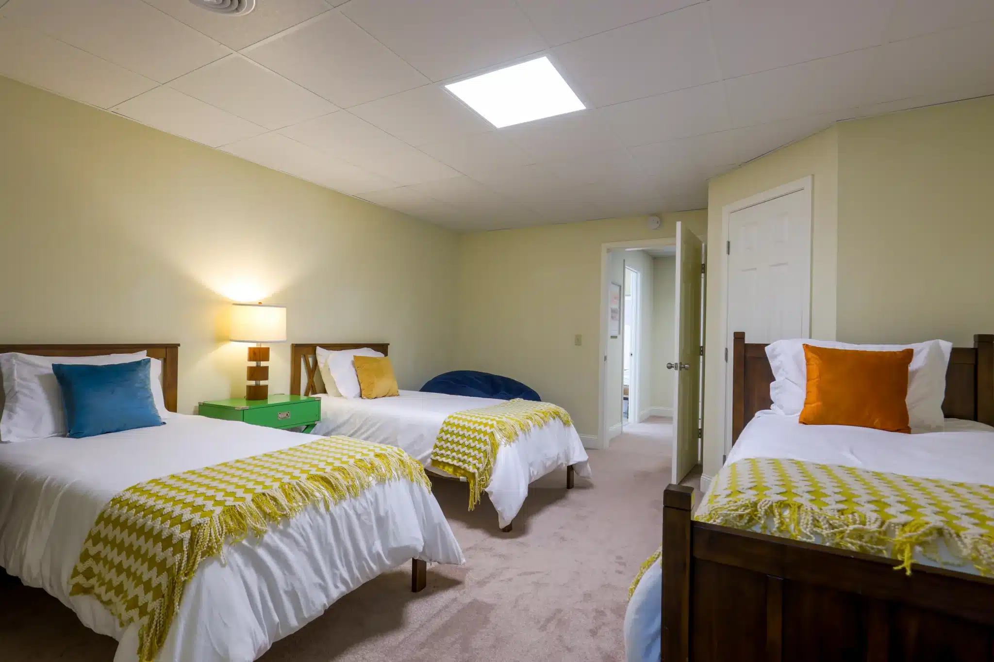 Bedroom with two twin beds, white bedding, yellow chevron throws, and a blue bean bag chair in a Clayton, GA vacation rental