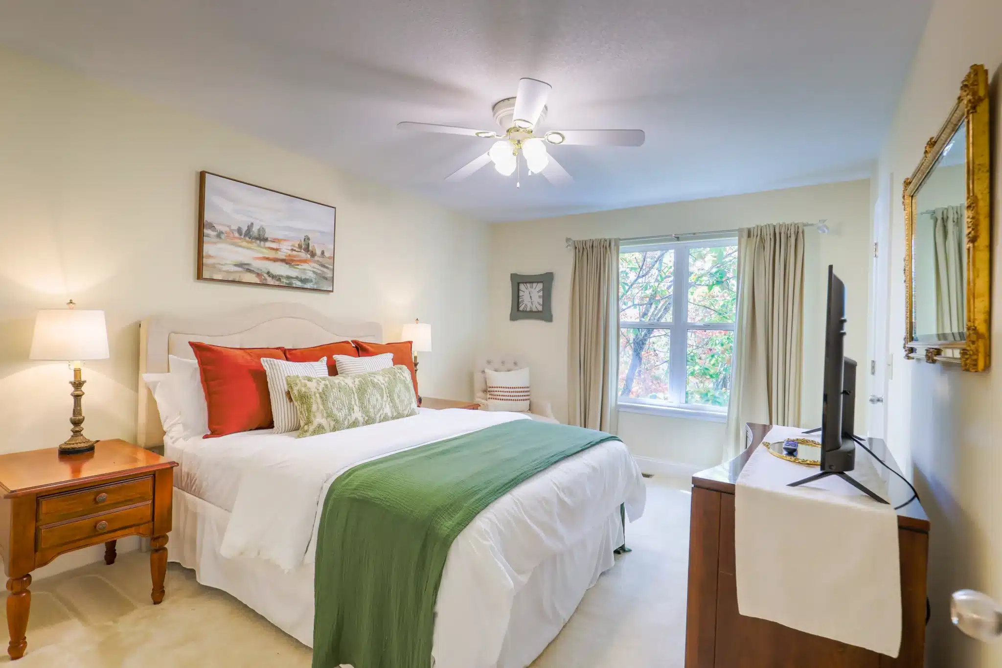 Bright bedroom with queen bed, white linens and striped pillows, autumn foliage through the window, in a Clayton, GA