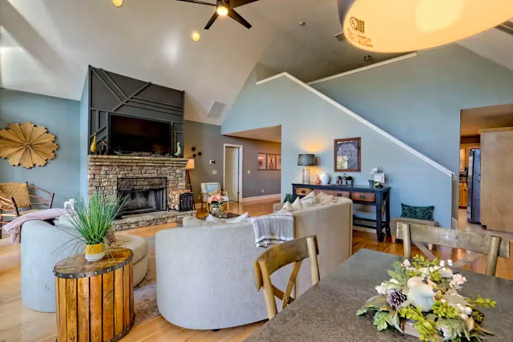 Open-concept living room with vaulted ceilings, stone fireplace, curved sofas in a cabin rental Clayton GA at Sunset Ridge